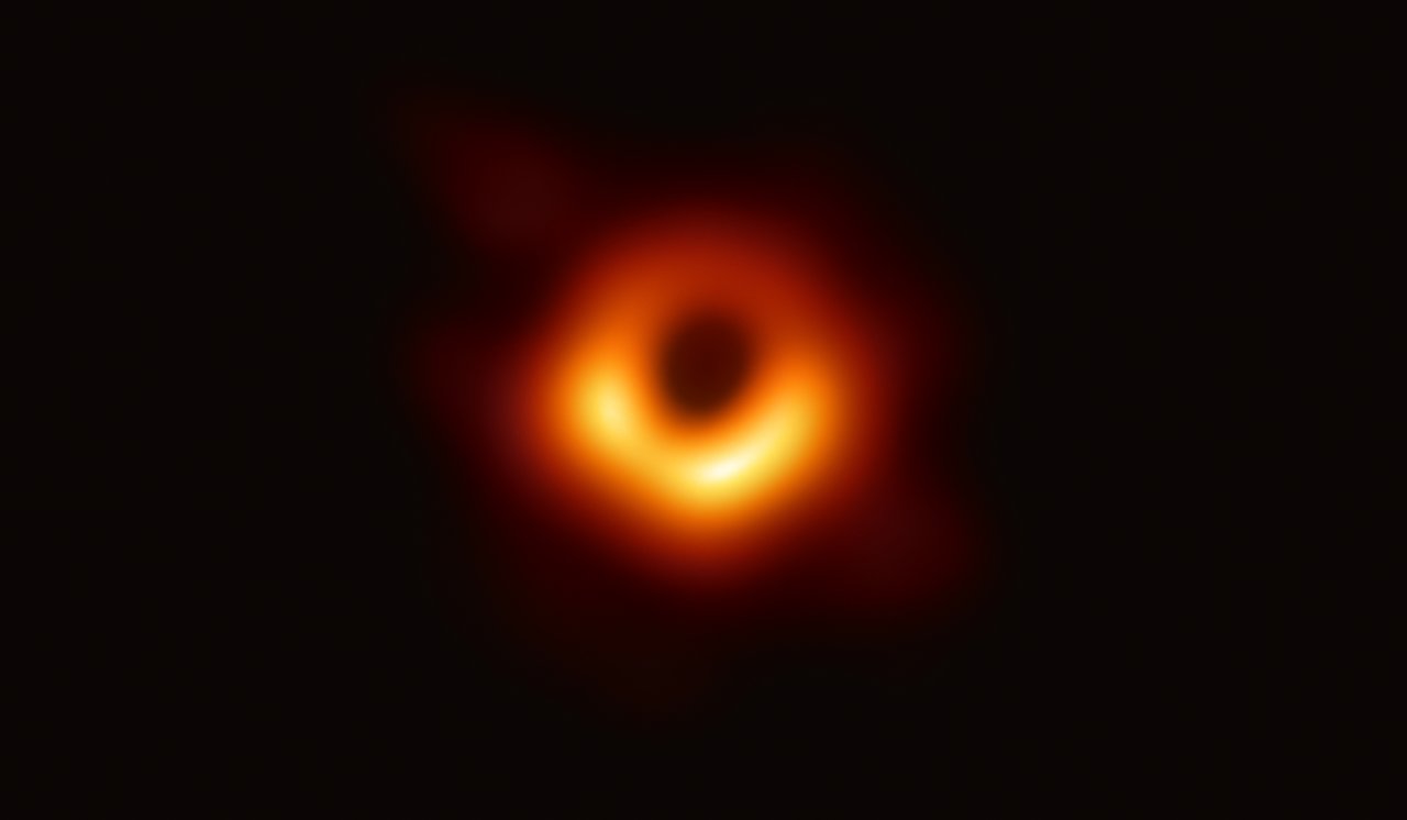 A fuzzy orange ring of light around a dark centre, brighter along the bottom.