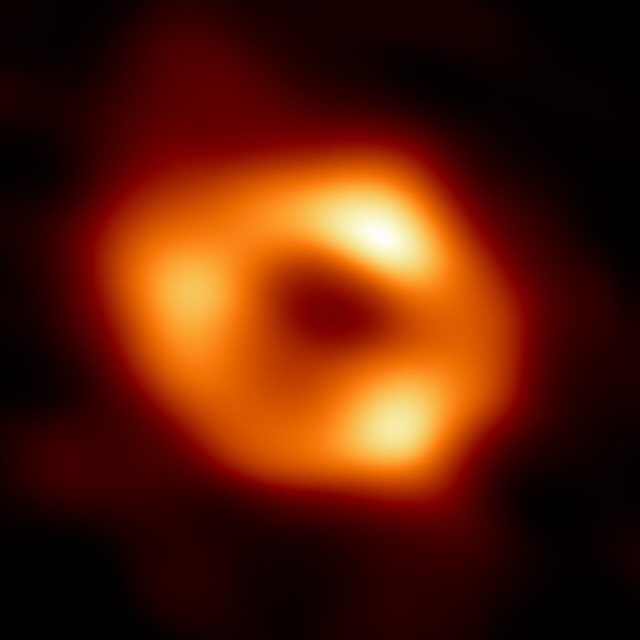 A thick orange ring of light with three brighter knots, around a dark centre.